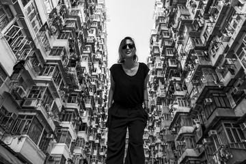 Woman in front of high-rise building with many units in Hong Kong