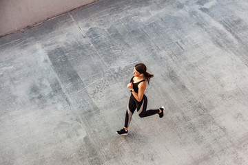 Top view of young attractive athletic woman speed running on city asphalt and workout in the...