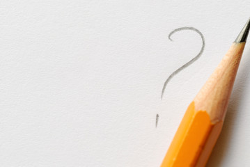 Pencil next to question mark on white paper