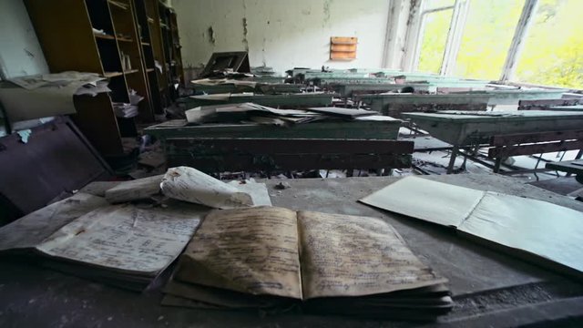 Close-up of students books lying on the shabby desk in the abandoned classroom. Inside the music school of Soviet Union in Prypiat left forever after the evacuation. Chernobyl exclusion zone.