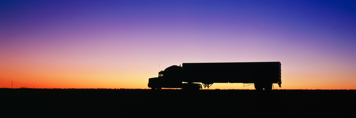 Silhouette of semi-truck against dramatic sky