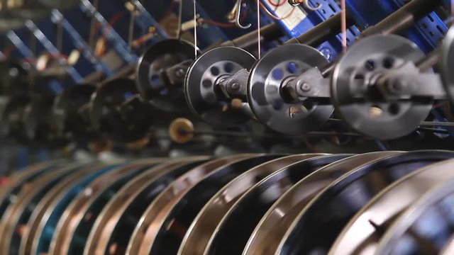 Bronze wire is fed for the manufacture of the side rings of automotive wheels. Reinforced steel bronze wire side ring on the tire. Tire manufacture robotic equipment on tire building plant at works.