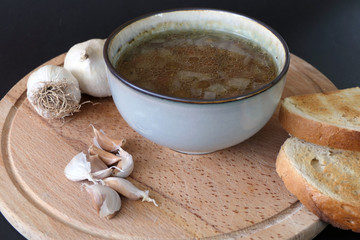 Warm Homemade Lentils Soup with Garlic and Bread Slices on a Dark Background