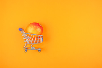 Mango fruit in shopping cart on orange background