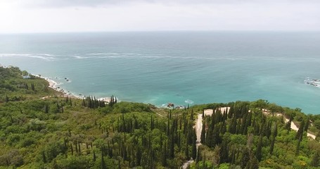 Aerial shot of a beautiful seaside landscape of an Adriatic sea in the summer. Quadcopter flies over the seacoast covered with green forest and flies to the turquoise sea 