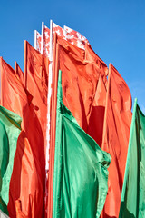 The flag of the Republic of Belarus, consisting of several flags, against the blue sky.