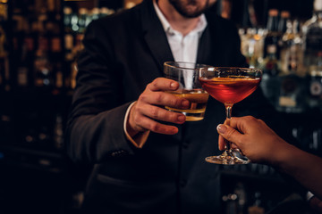 Elegant man and woman are consuming alcohol at the posh restauraunt together.