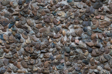 Concrete plaster interspersed with many smooth river stones. Decorative wall. Seamless pattern.