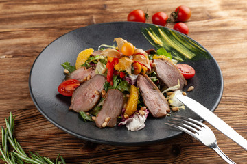 Gourmet mixed salad with smoked duck breast, cherry tomatoes, orange and pine nuts, flavoured with citrus dressing