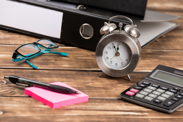 business place with folder, glasses, clock calculator and pen