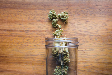 A glass Jar of Medical Marijuana on a wooden table