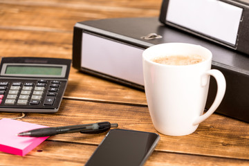 desk with coffee cup, folder, paper, pen and calculator