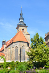 Fototapeta premium Vertical picture of historical Franciscan Monastery in Plzen, Czech Republic shot from the park in Krizikovy sady. Medieval architecture, attraction. Pilsen, Western Bohemia, Czechia. Sunny day