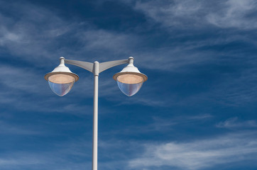 Freestanding street lamp in gray against a blue sky