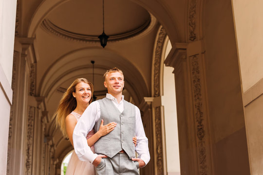 The bride embraces the groom from the back side and smile. corri