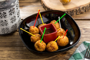 Fried potato cheese balls or croquettes with tomato ketchup on wooden table