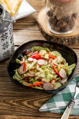 Plate of healthy green garden salad with fresh vegetables on wooden table