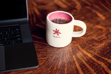 cup of coffee on wooden background with laptop