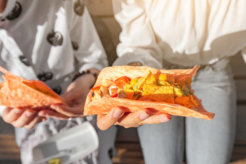 Two girls eat traditional Mexican fast food tacos and drink michelada on the street. Communication and takeaway food concept