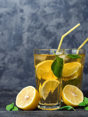 Two glasses of Mojito or lemonade on a dark table. Drink with lemon and mint