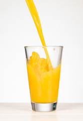 pour orange juice in a glass with splashing
