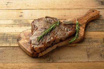 Marbled beef steak on rosemary board, on wooden background, restaurant menu, gastronomy, delicious food