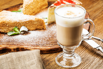 Cappuccino Cup with latte on wooden background. Beautiful foam, green ceramic Cup.