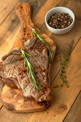 Marbled beef steak on a board with rosemary pepper, spices, on a wooden background, restaurant menu, gastronomy, tasty food