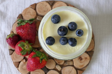 Homemade Yoghurt in a Jar with Fresh Strawberries and Blueberries on a Wooden Background