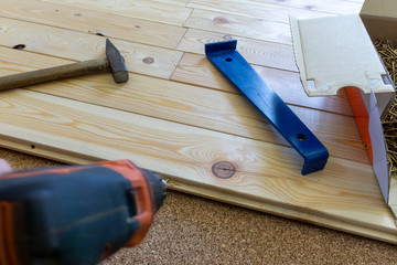 professional carpenter installs natural wooden planks on cork floor in empty unfinished room under...