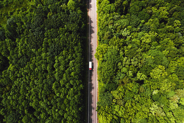 Aerial view of a road in the middle of the forest. Cars on the road driving.