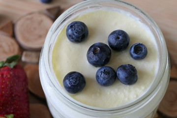 Homemade Yoghurt in a Jar with Fresh Strawberries and Blueberries on a Wooden Background