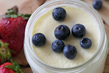 Homemade Yoghurt in a Jar with Fresh Strawberries and Blueberries on a Wooden Background