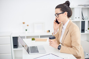 Businesswoman talking on the phone with a Cup of coffee in his hand