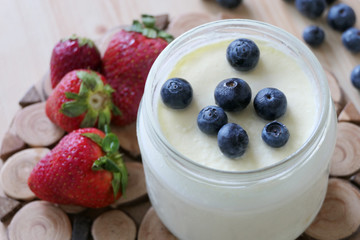 Homemade Yoghurt in a Jar with Fresh Strawberries and Blueberries on a Wooden Background