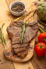 Marbled beef steak on a board with rosemary pepper, seasoning, and fresh vegetables on a wooden background, restaurant menu, gastronomy, tasty food. Restaurant service, verikalnoe photo, banner