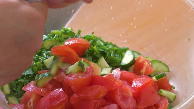 hands cut salad with fresh tomatoes and cucumbers with greens
