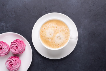 Cup of coffee and homemade pink marshmallow on black stone background Top view