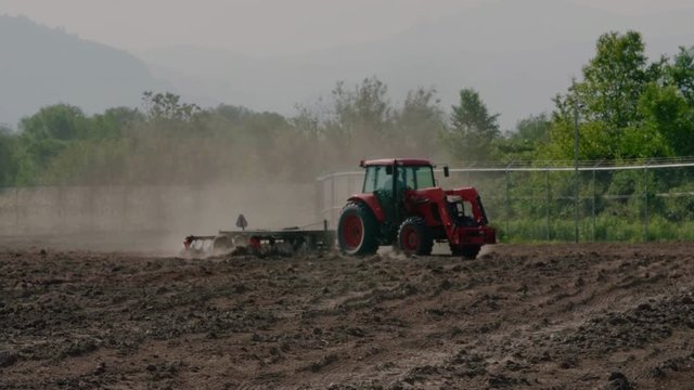 Tractor Pulling Disc Harrow Through Field in Preparation for Planting, Agriculture, Canada