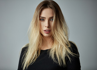 Fototapeta premium Blonde woman with long straight hair looking at camera isoalted on gray background