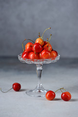 Berries of yellow sweet cherry in a glass vase. Drops of water are visible on the berries of ripe sweet cherry. Close-up. Vertical frame orientation. 