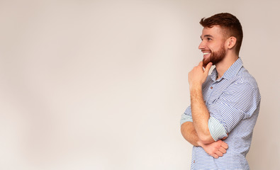 Young smiling man thinking and looking away on free space