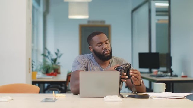African man connecting camera to notebook. Man recording photos to computer