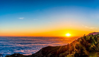 Panorama of Setting Sun at Sunset over Layer of Clouds