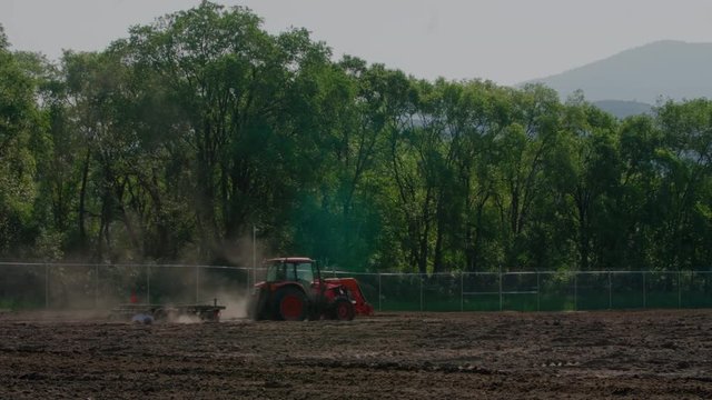 Tractor Pulling Disc Harrow Through Field in Preparation for Planting, Agriculture, Canada