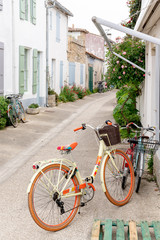 Fototapeta na wymiar street in Ile de Re with white house green shutter and beach cruiser bike