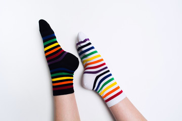 Woman legs wearing funny bright different striped colorful socks on white background with copy space. Flat lay