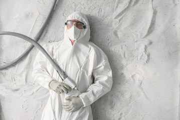 A man in white protective uniform, respirator and plastic transparent glasses.