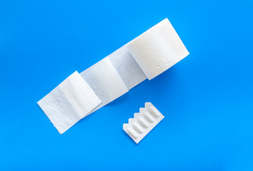 Toilet paper roll and rectal suppository for proctology diseases concept on blue background top view