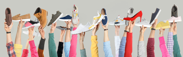 Set of people holding different stylish shoes on color background, closeup